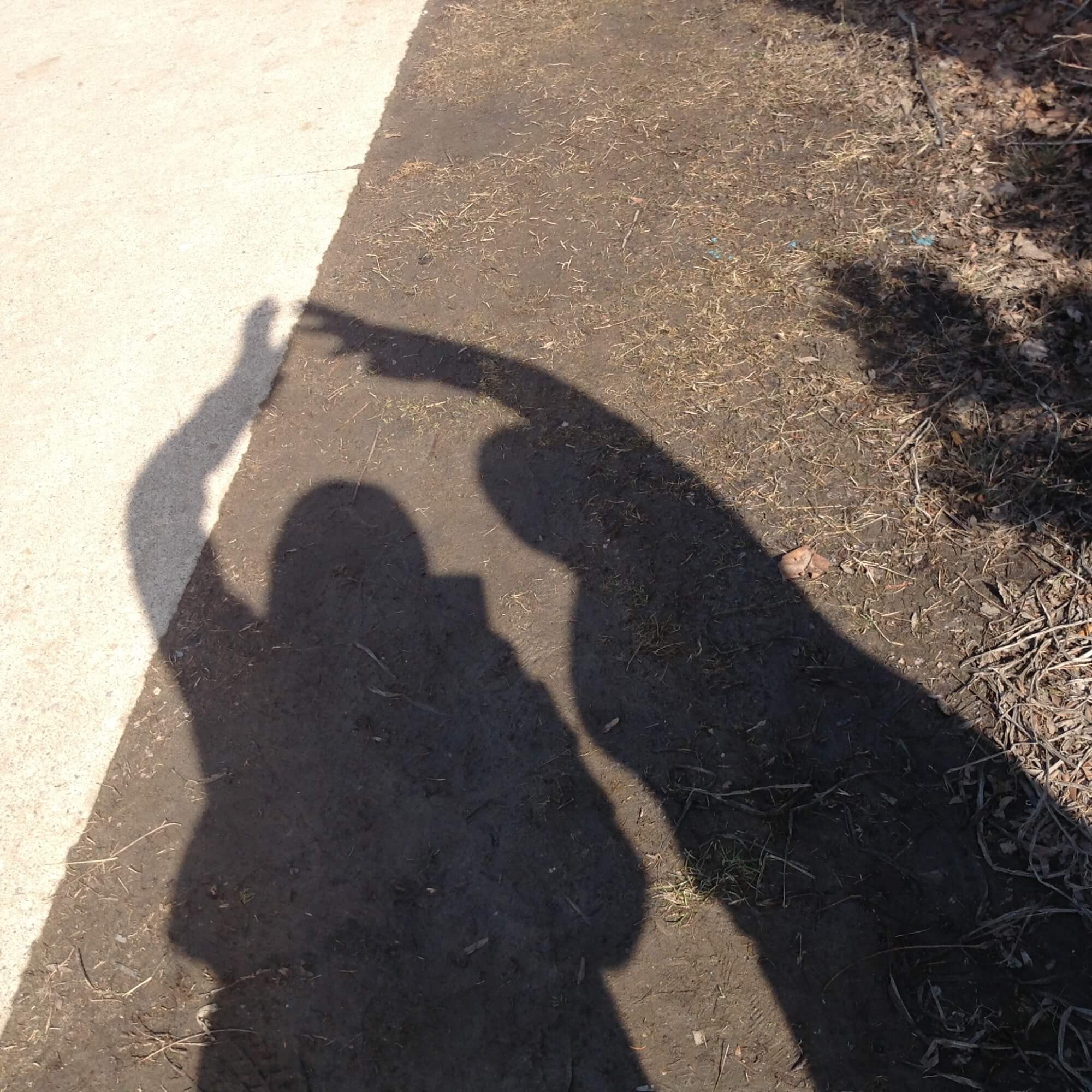 Two children photographing their shadow on the ground