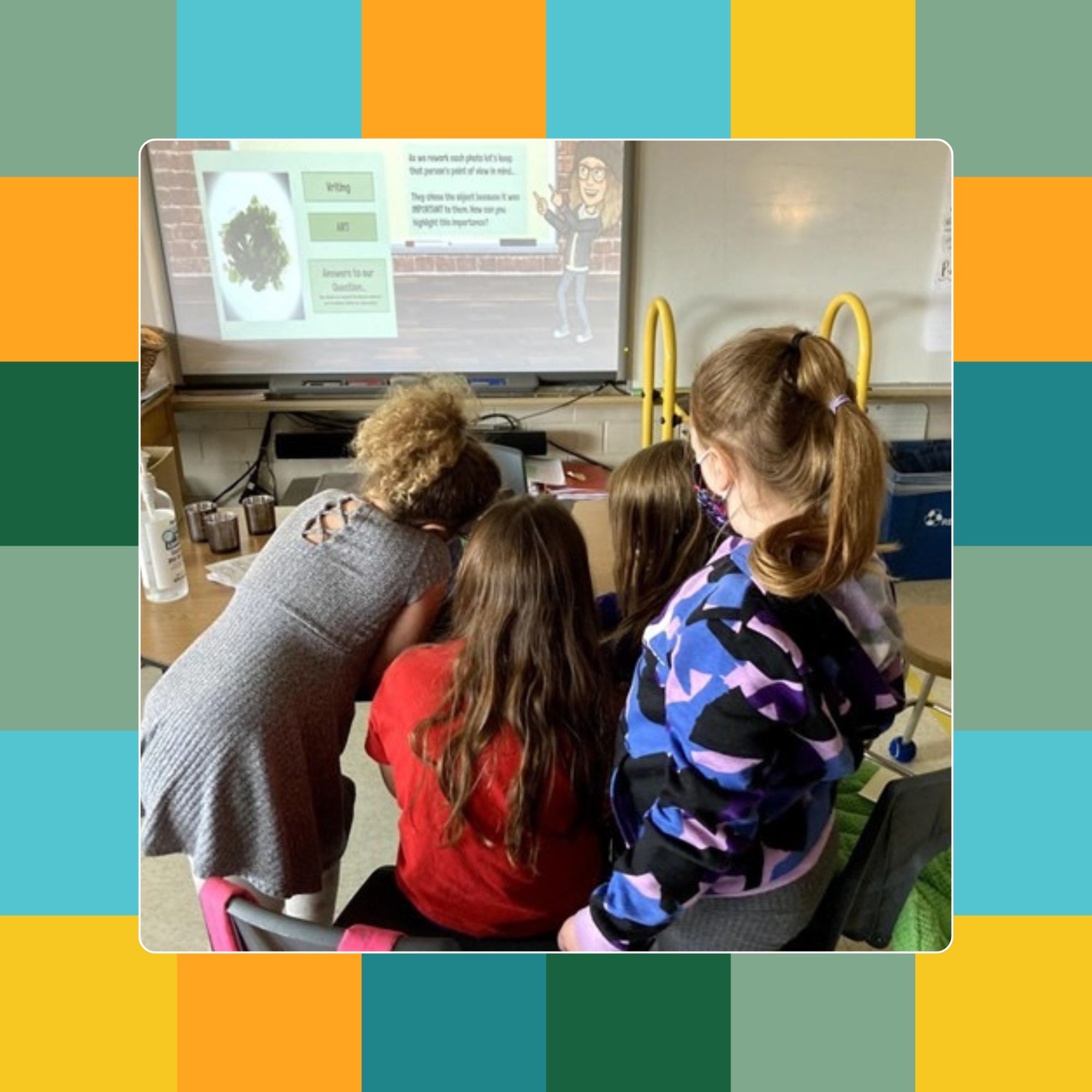 Three children gathered around a computer in a classroom setting.